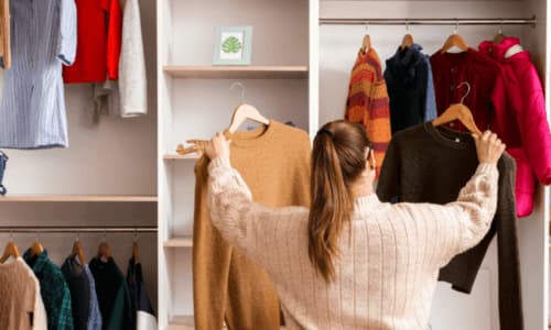 Een vrouw die niet weet wat ze aan moet trekken staat voor de kast